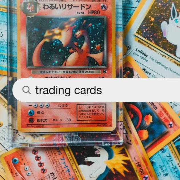 Collection of trading cards on a wooden surface with a magnifying glass overlay and 'trading cards' text.